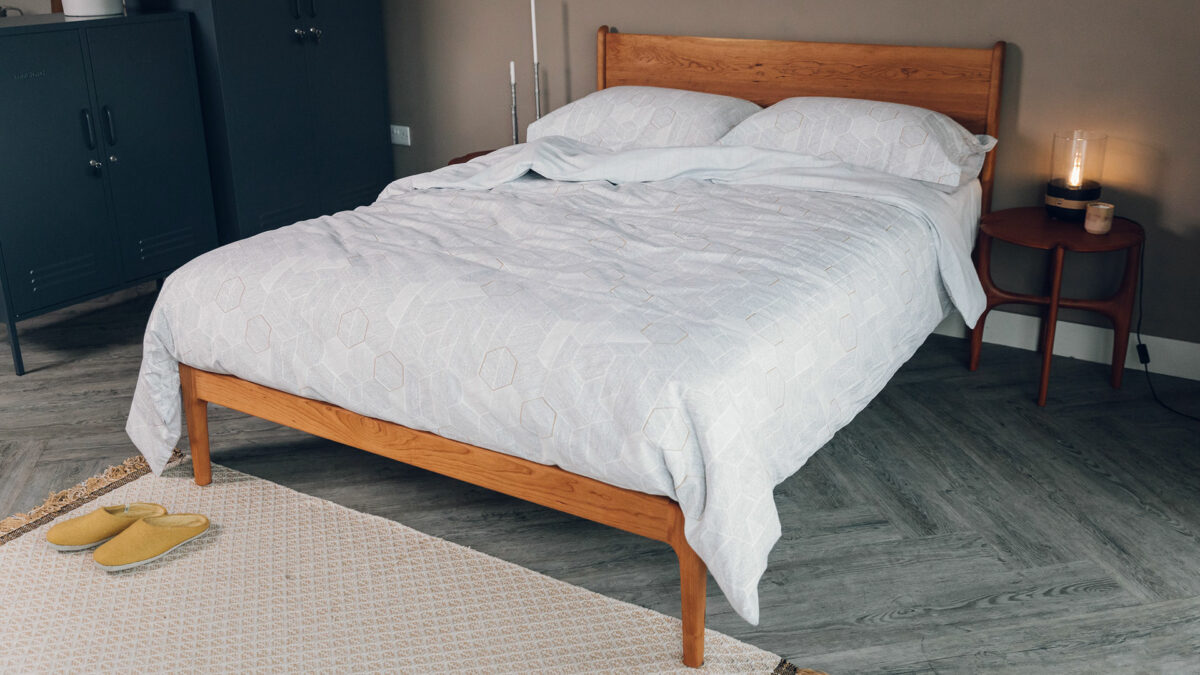 reversible duvet set with a hexagonal print in grey shown on a kingsize cherry wood bed