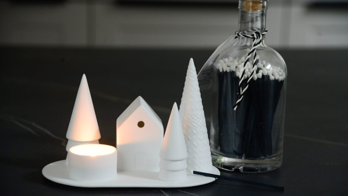 Christmas scene porcelain tea light holder with snowy trees and a house shown with candle lit