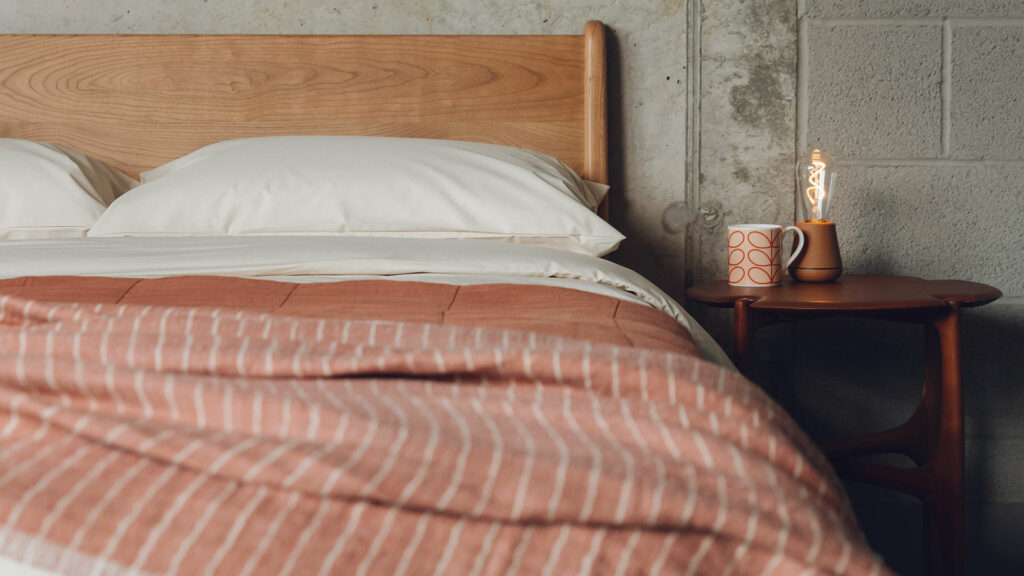 mid century bedroom style with a low cherry wood Carnaby bed and rich curvy mahogany side table