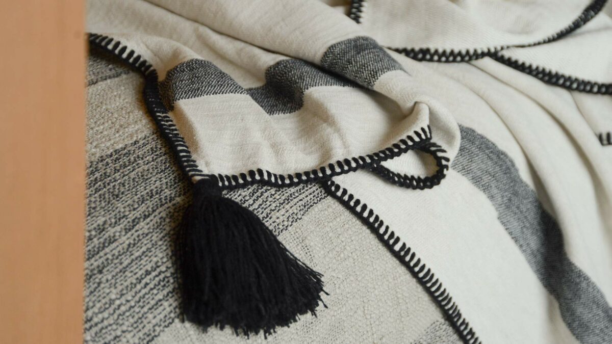 woven cotton bed throw in ivory and black with black tassel and stitched edge