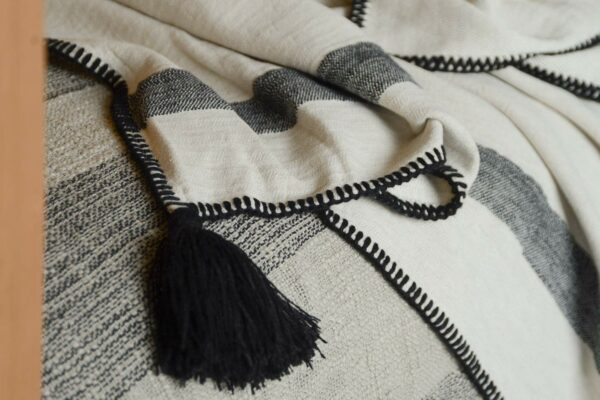 woven cotton bed throw in ivory and black with black tassel and stitched edge