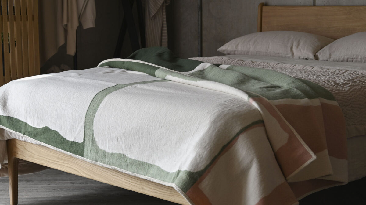 Green and pink abstract throw laid over the top of stone bedding.