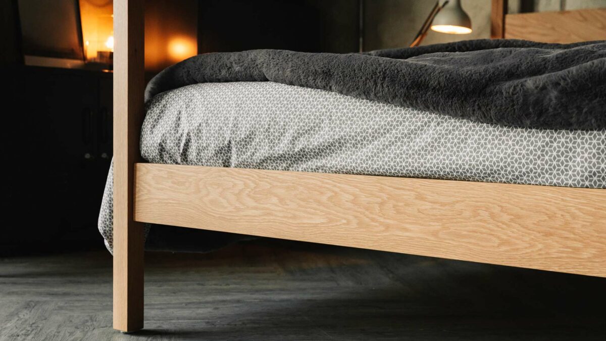 A close up view of the foot board end and post of our Kelham 4 Poster bed in solid wood - oak