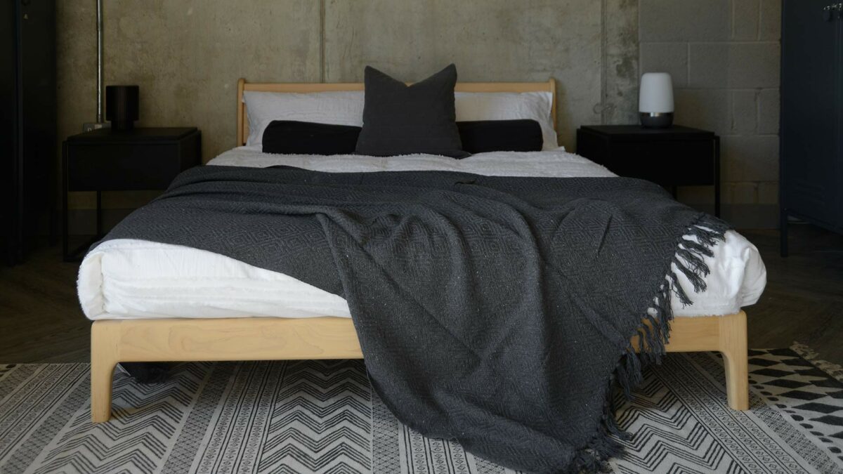 charcoal grey textured cotton rich throw shown on a kingsize wooden bed