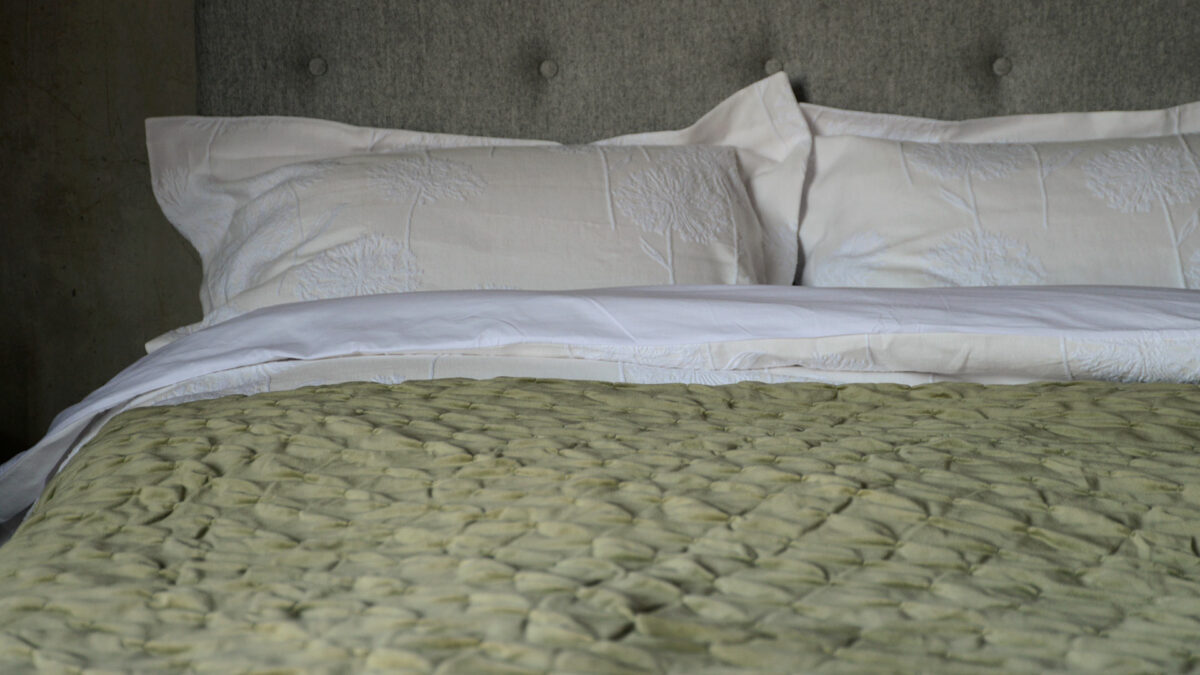 sage green velvet softly quilted reversible bedspread shown on a kingsize bed