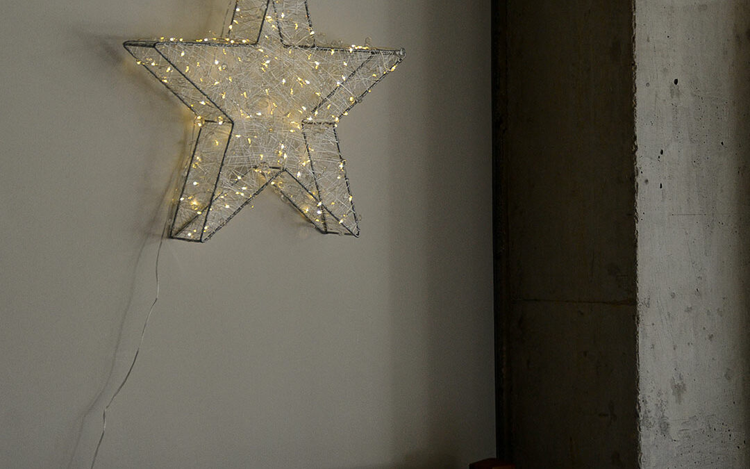 filigree light-up star decoration shown hanging by a wall