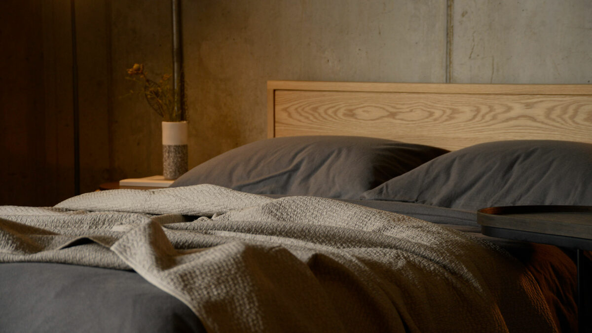 diamond stitched quilted bedspread in taupe shown on a wooden framed bed