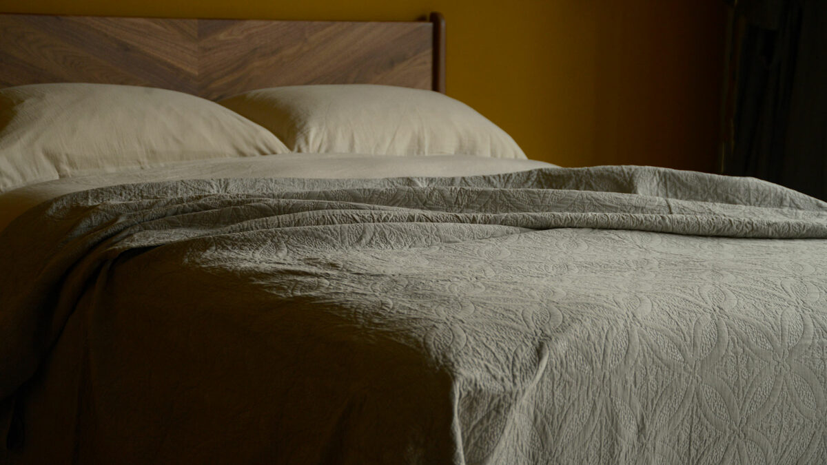 soft suede touch quilted effect bedspread in taupe shown on a kingsize bed