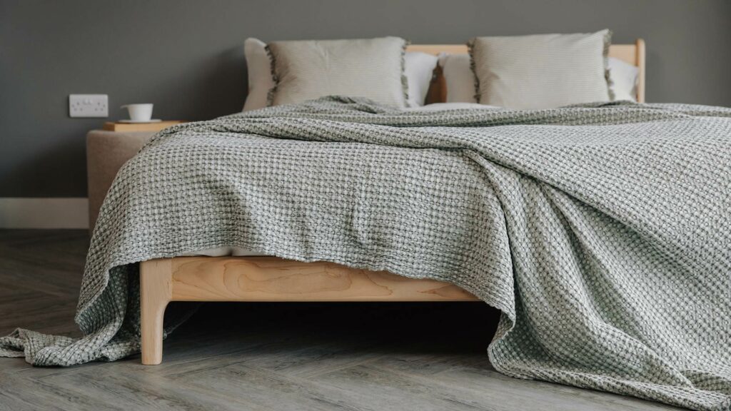 Silver-Green Bedspread displayed on a solid maple bed base