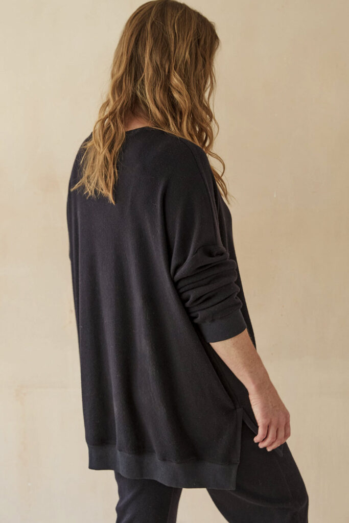 Model wearing long midnight blue sweatshirt, facing away from camera.