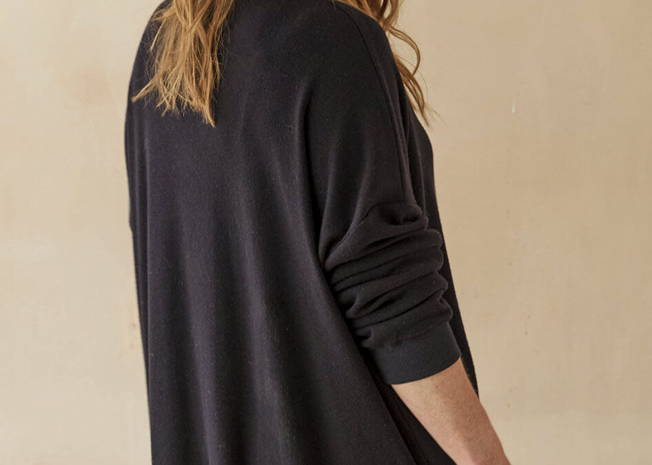 Model wearing long midnight blue sweatshirt, facing away from camera.