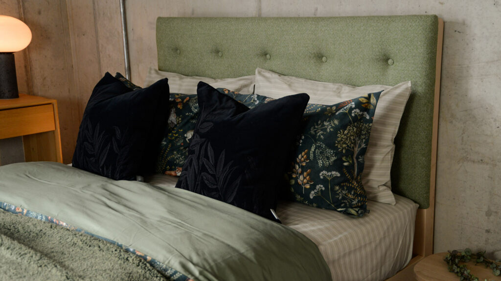 black velvet cushion with black embroidered leaves design shown on a kingsize bed