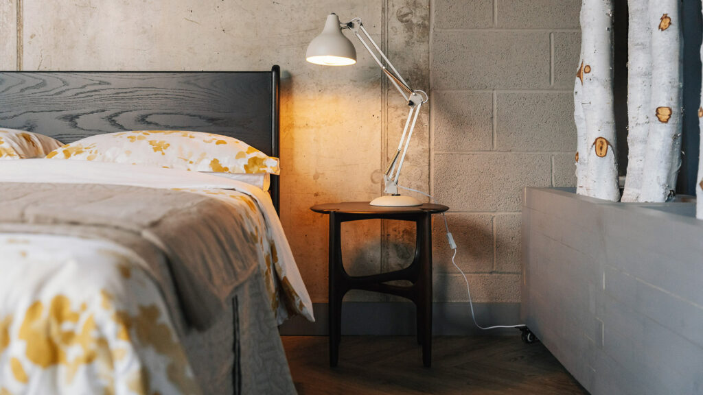 sculptural mid century style dark mahogany side table used as a bedside table