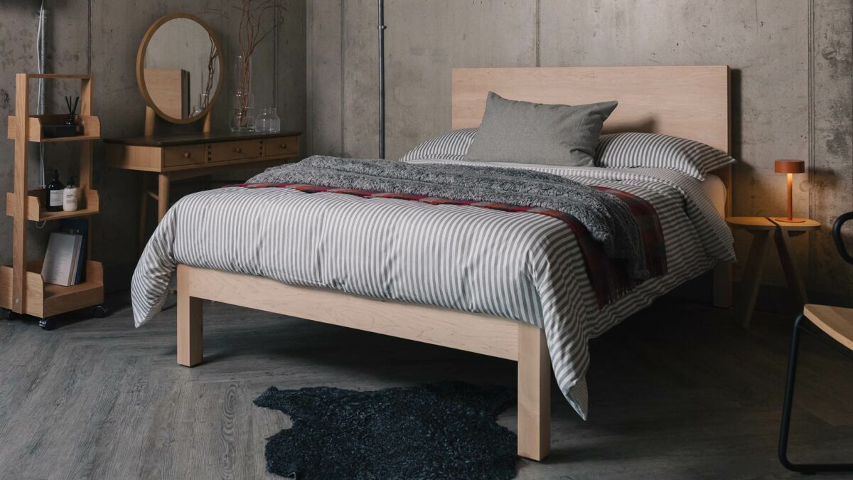 maple Bamford modern bed with grey and red bedding and orange bedside lamp