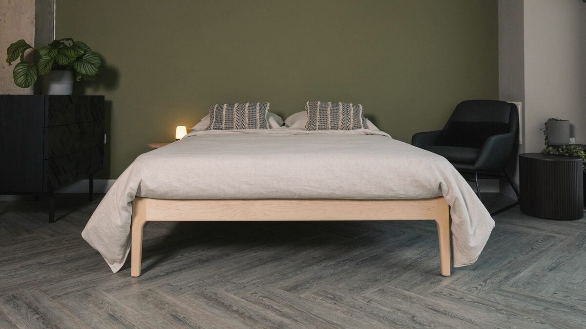 Maple wood Camden bed frame without a headboard and shown with taupe linen bedding