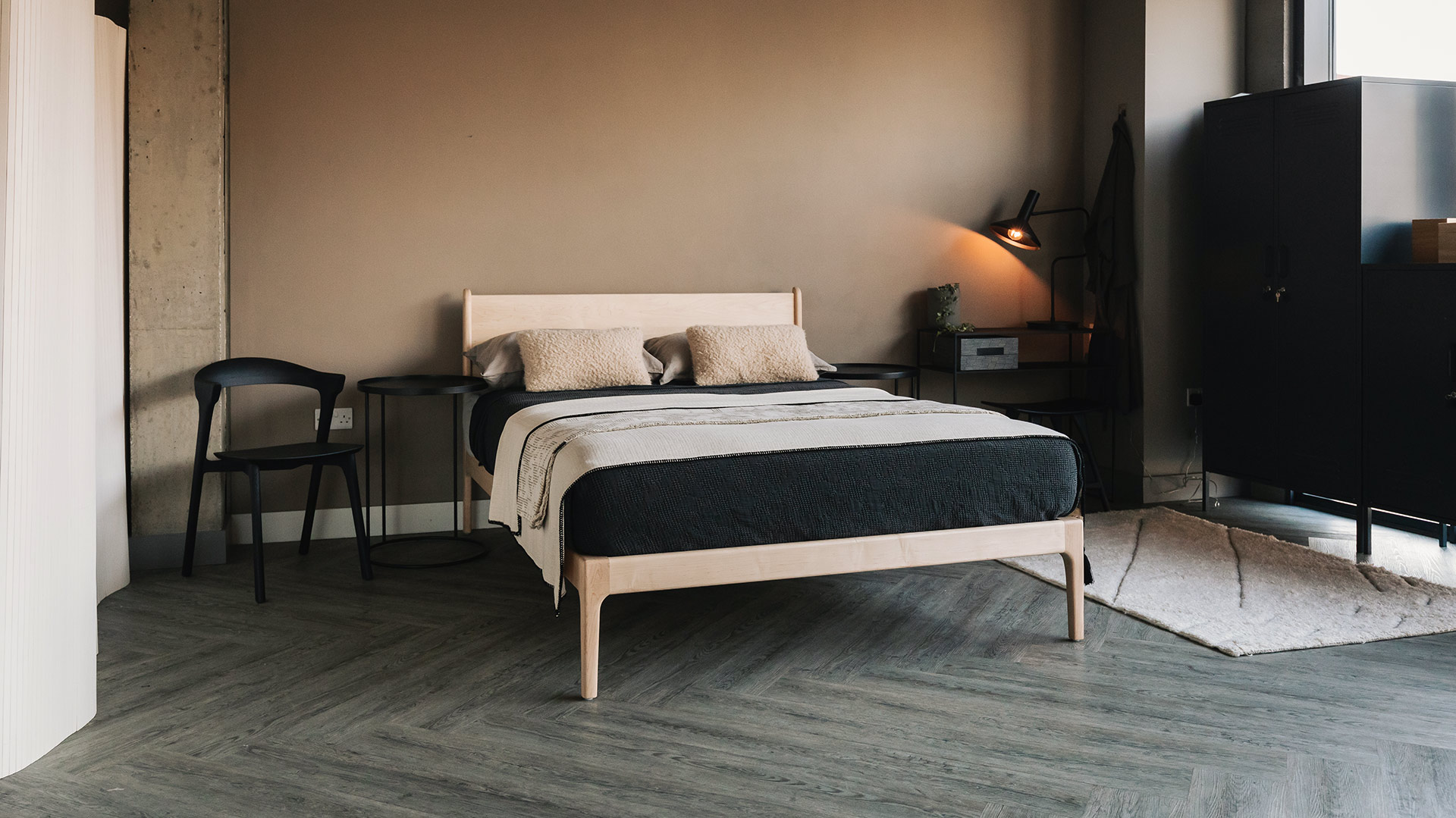 Scandi bedroom look with stone coloured walls, a solid maple wood bed and dark grey storage lockers