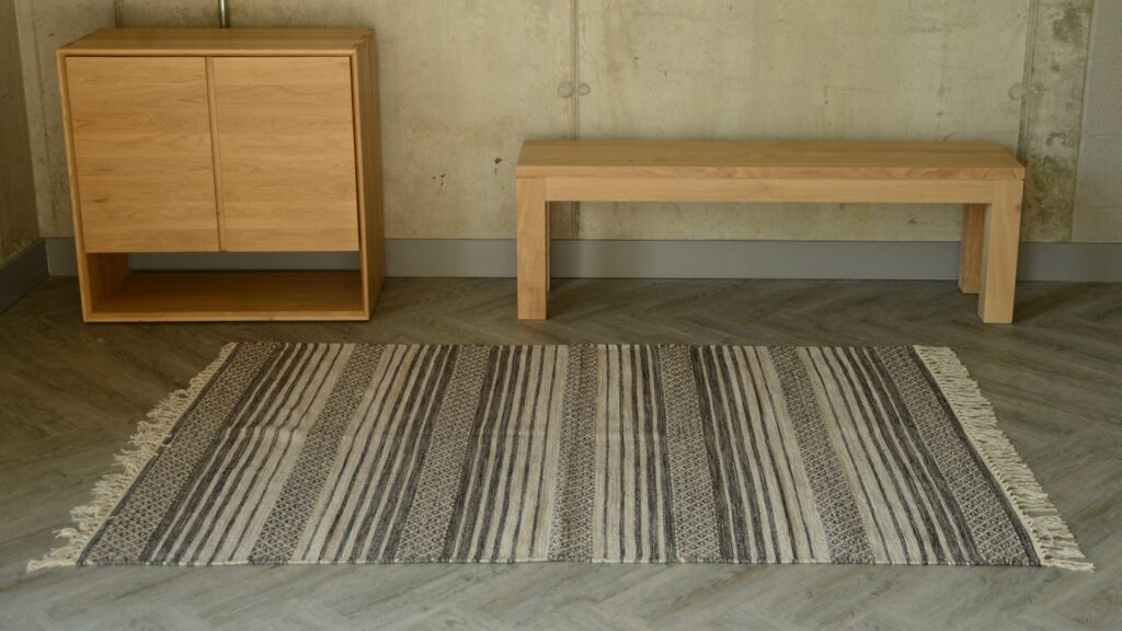 woven rug in ecru and charcoal with fringed detail