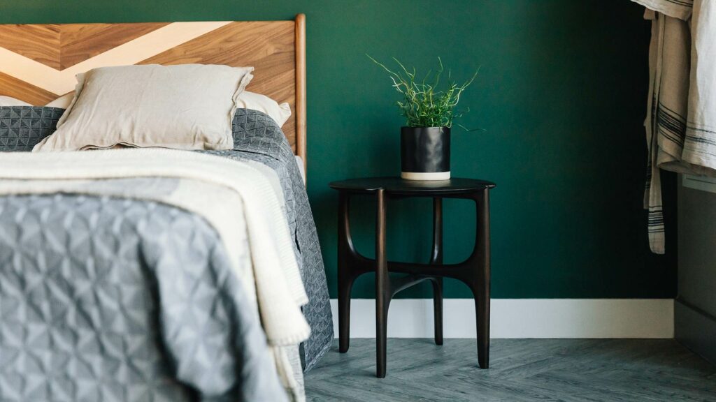 sculptural dark mahogany side table used as a bedside table