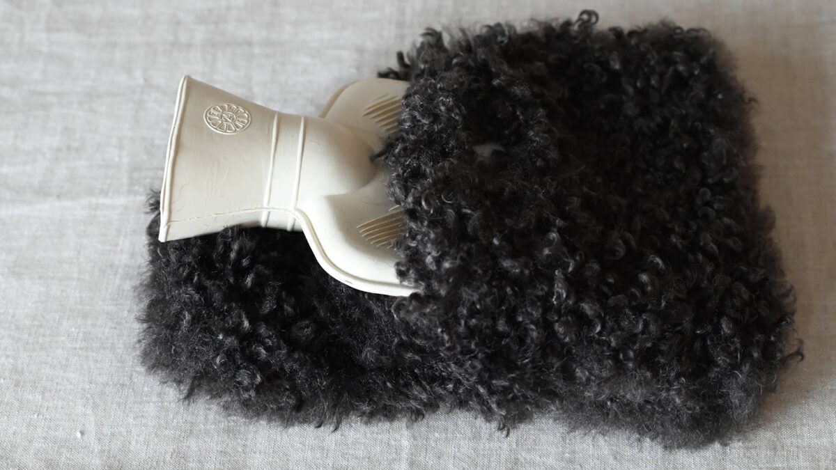 Mini hot water bottle with dark brown faux fur cover.