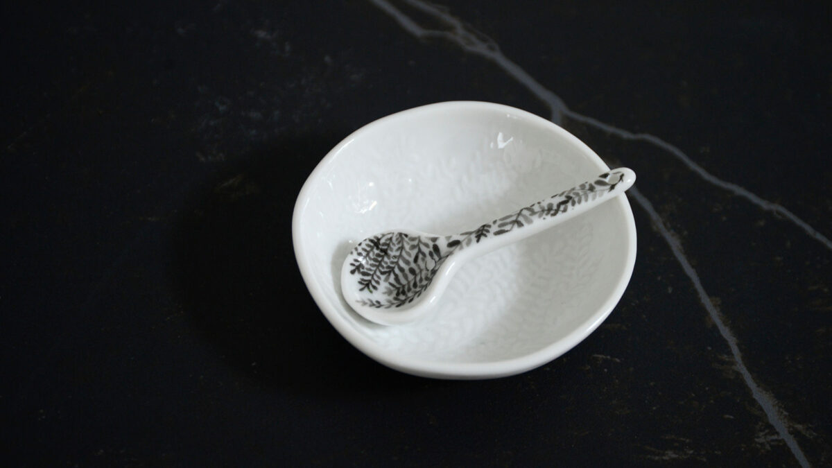 small pretty white porcelain bowl with embossed leaf pattern to the bowl and a grey leaf pattern to the spoon