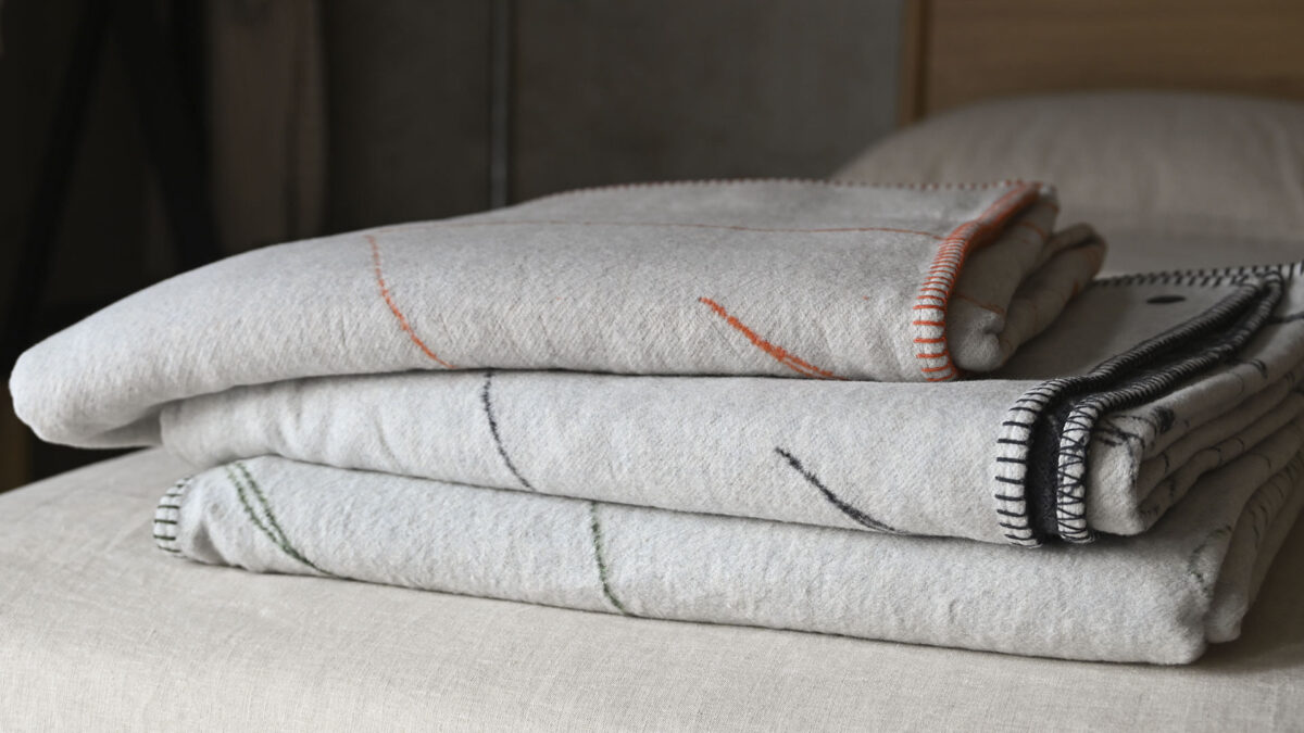Three ivory floral patterned throws neatly folded and stacked.