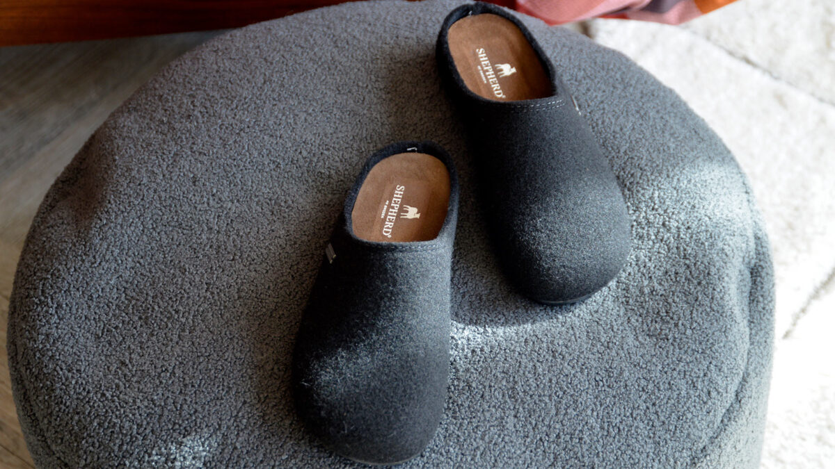 black wool slippers on grey pouffe.