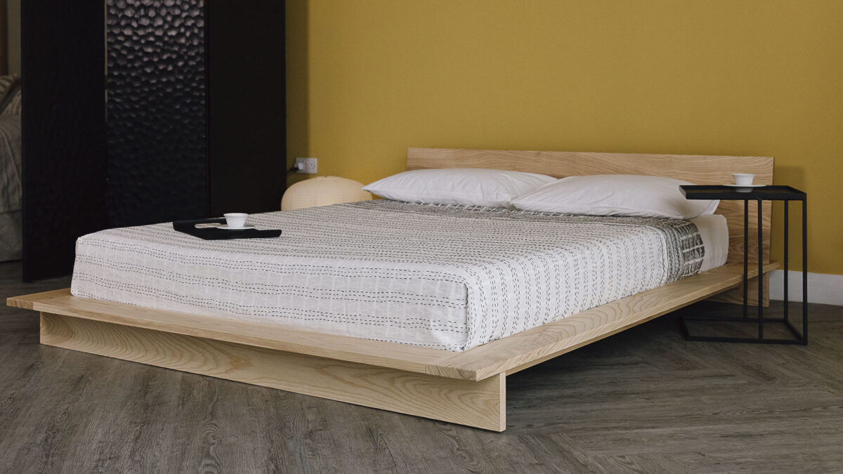 3/4 view of the Oregon bed frame in ash, with a metal side table.