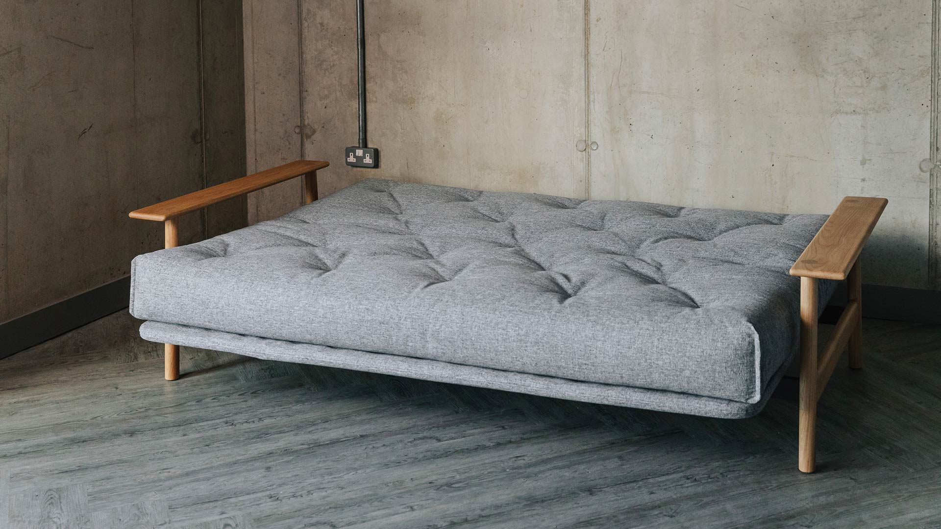 sofa bed with oak arms shown flattened to make a bed