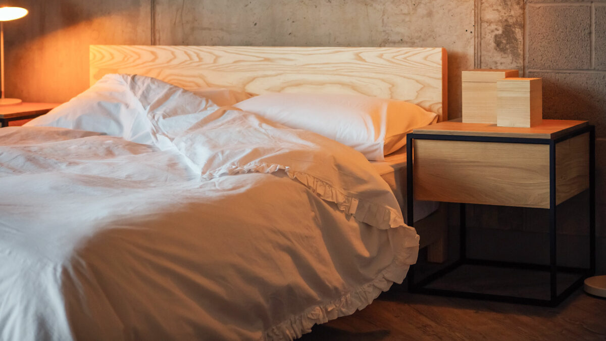 White ruffle edged cotton bedding on low wooden Sonora bed shown with Monolit bedside table