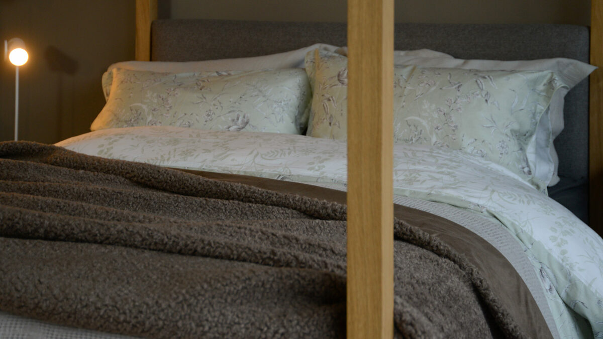 softest sheepskin effect throw in brown shown on a bed