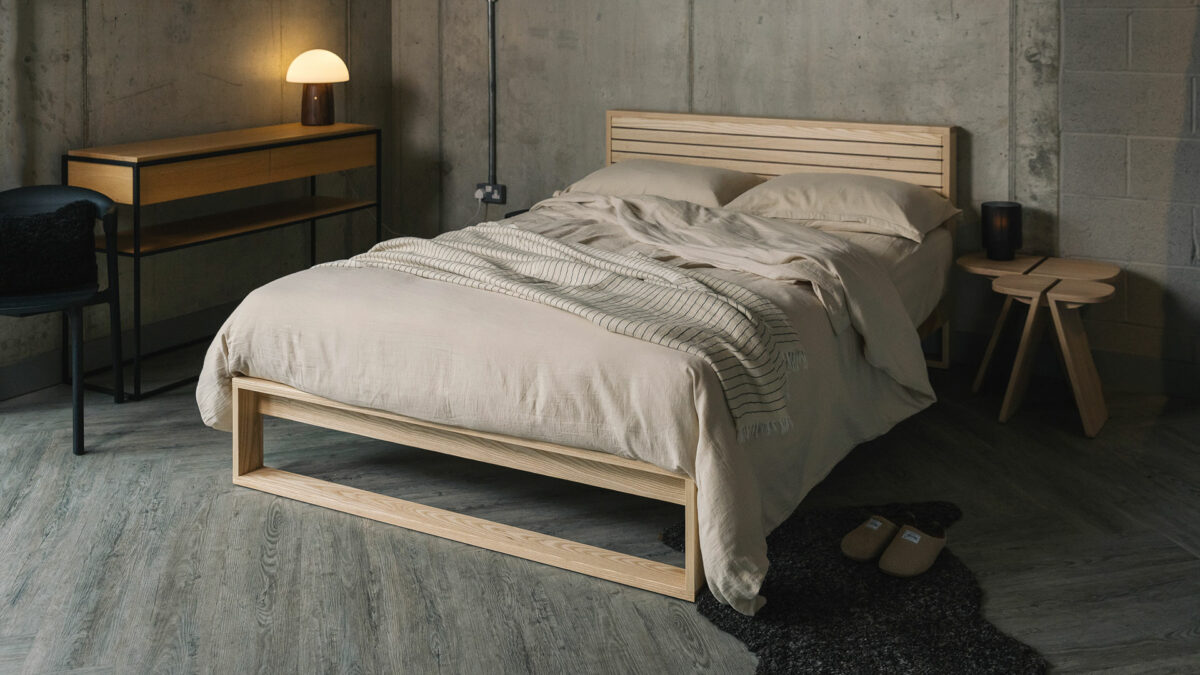 A special edition Leith bed in Ash wood with walnut stripes to the headboard panel shown with stone coloured bedding