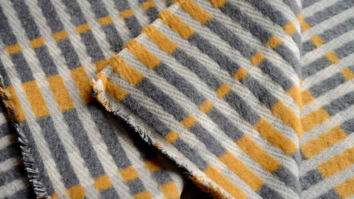 patterened fluffy throw in grey and ochre tones shown close up