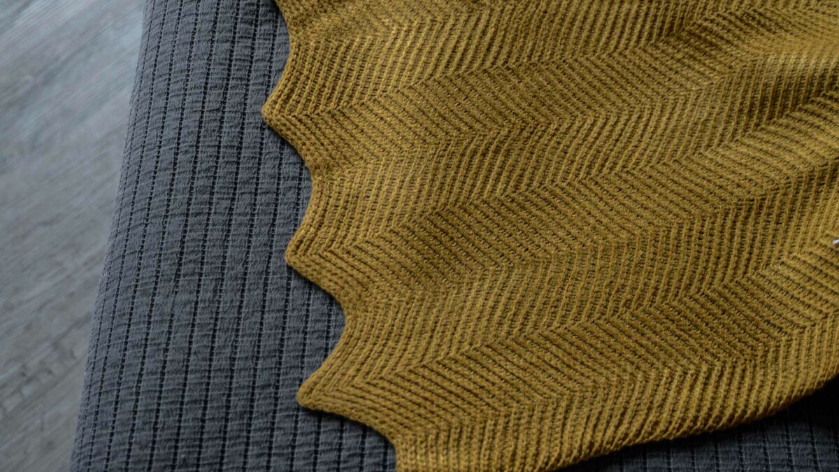 knitted throw in mustard yellow a close up view of the scalloped edge