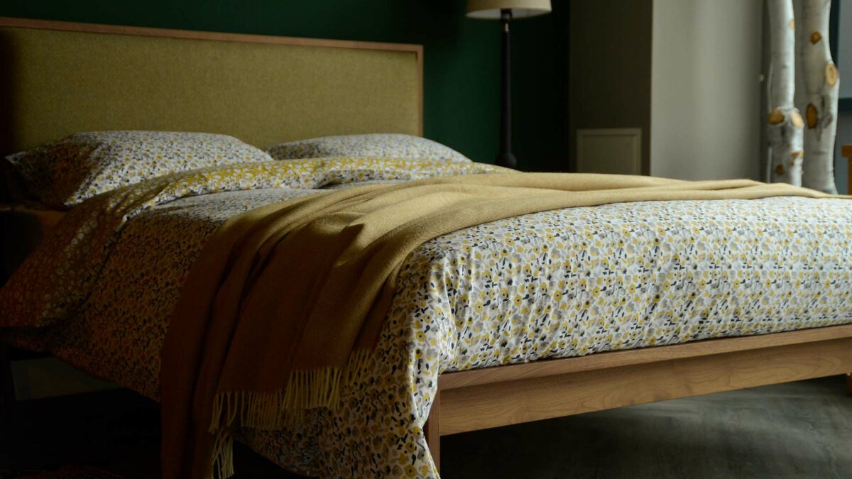 floral patterned reversible duvet cover set in yellow ochre and grey shown on a bed