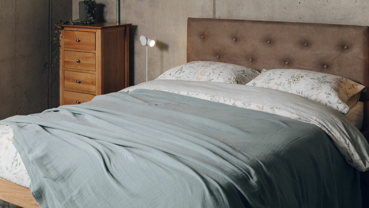 muted aqua coloured bedspread with a crinkle texture shown on a kingsize bed