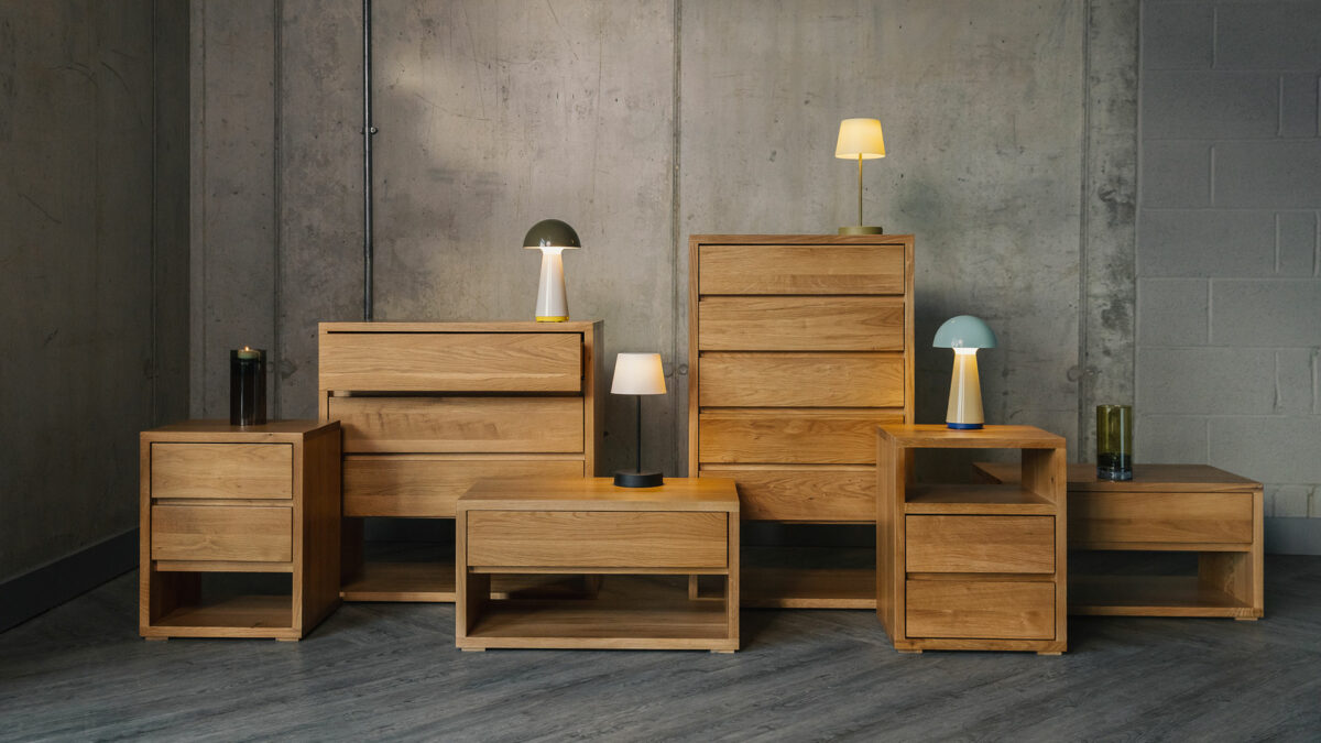 Black Lotus Cube range of solid oak bedroom storage chests in a range of sizes shown with colourful table lights