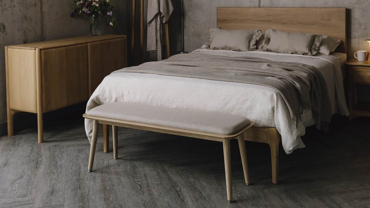 Bedroom scene with oak bed and furniture and neutral bedding.