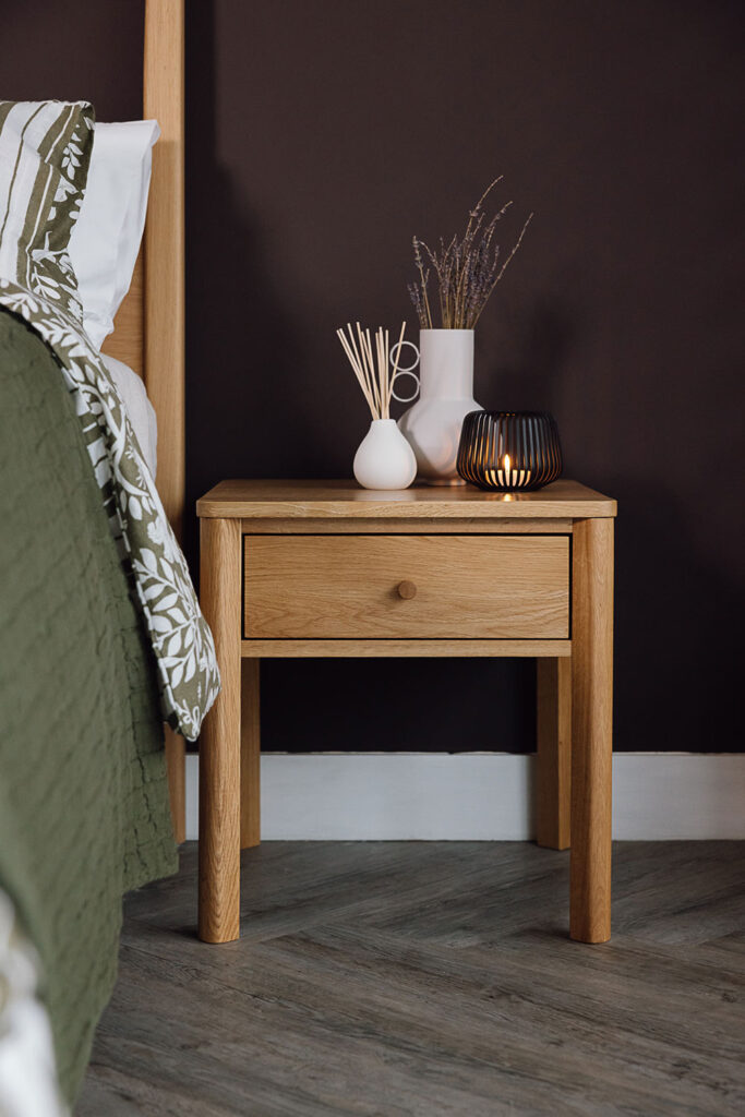 Oak bedside table with drawer. Vase, diffuser and candle holder on top.