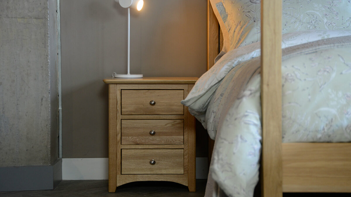 classic oak bedside table with 3 drawers shown with our Highland 4 poster bed