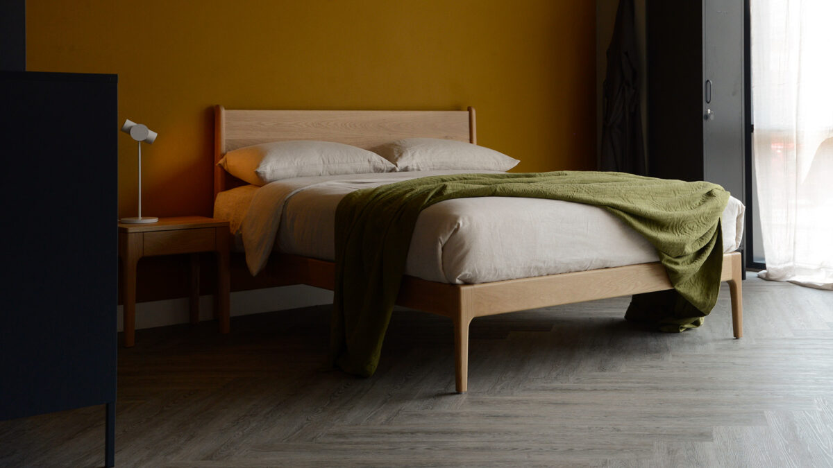 Our retro style Camden bed made from solid oak wood shown with matching bedside table and ecru linen bedding