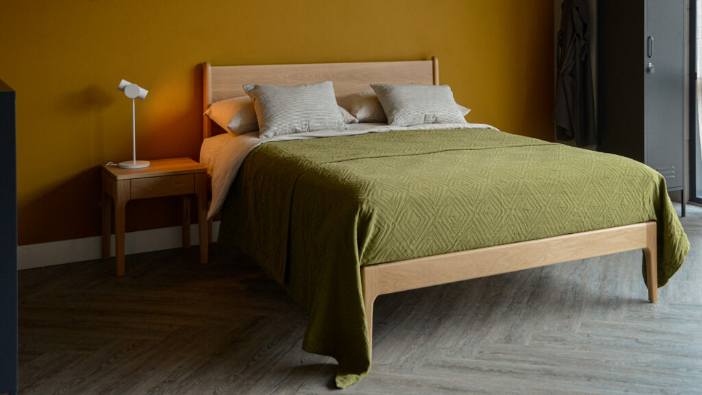 Our retro style Camden bed made from solid oak wood shown with olive green textured bedspread