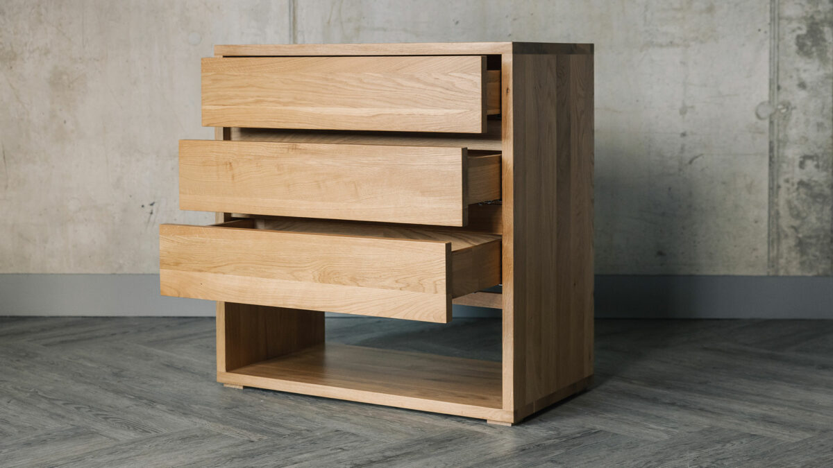 A solid oak bedroom storage chest with 3 drawers shown open