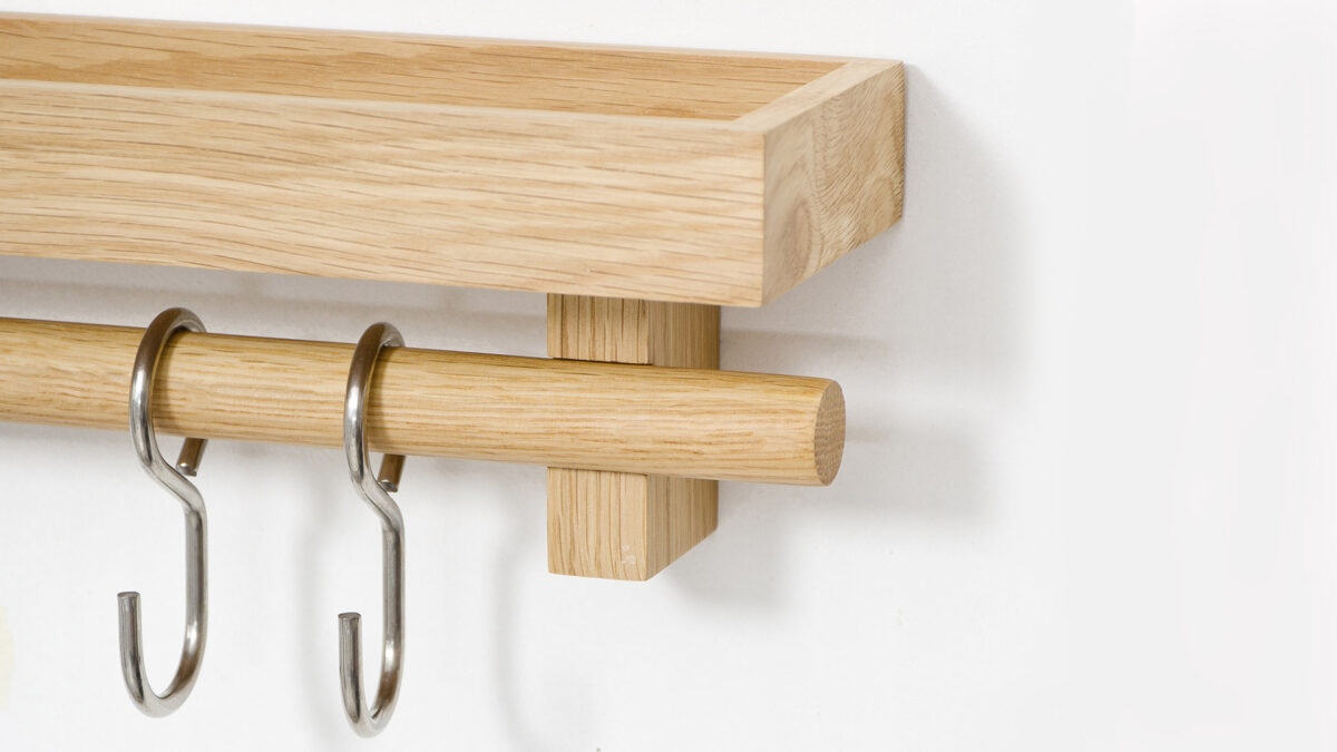 a close up view of the box edged oak wall mounted storage shelf with utensil hooks