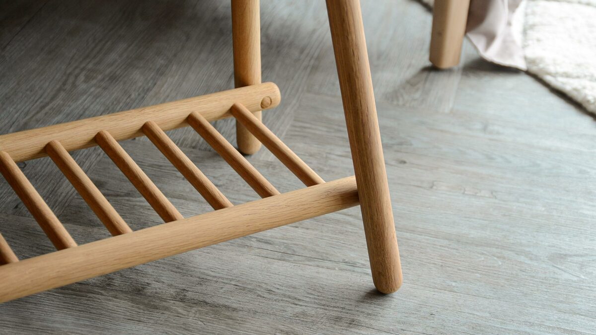 a close up of the spindle storage shelf and rounded legs of this small oak bench