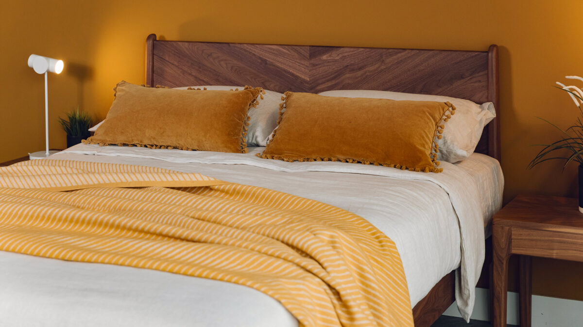 ochre velvet cushions with striped bedspread on walnut hoxton bed