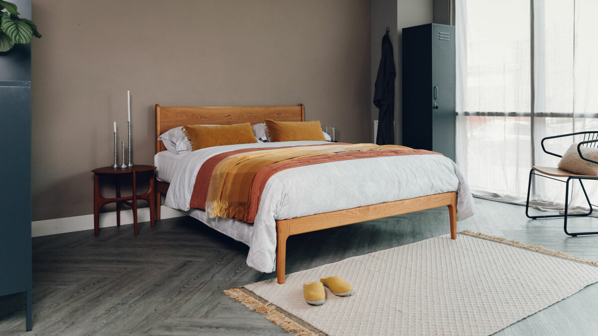 oiled cherry bed with ivory and ochre bedding with pi side table and mustard mix rug