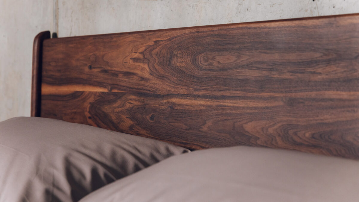 a close up view of the Camden bed's deep walnut wood oiled finish headboard