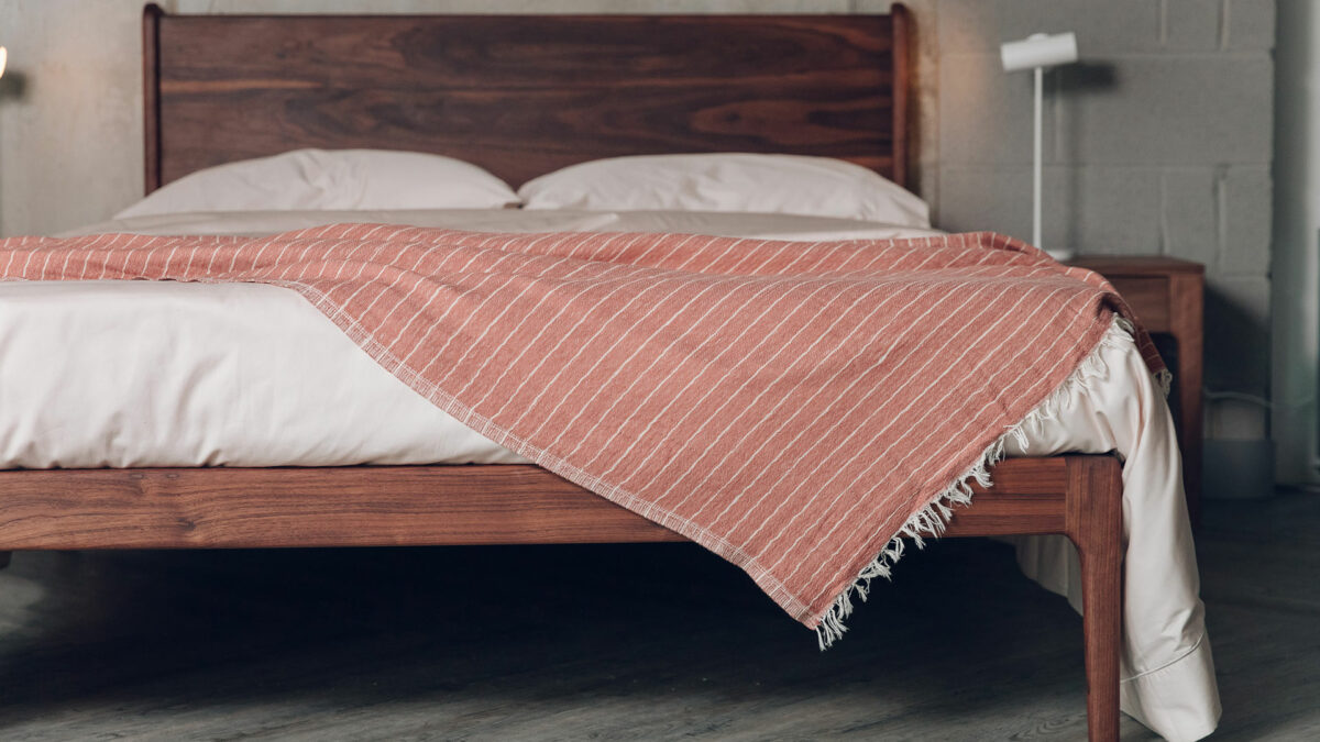 deep walnut wood Camden bed with a draped terracotta coloured striped throw