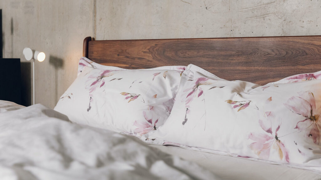 soft pink floral print pillowcases shown against a walnut headboard