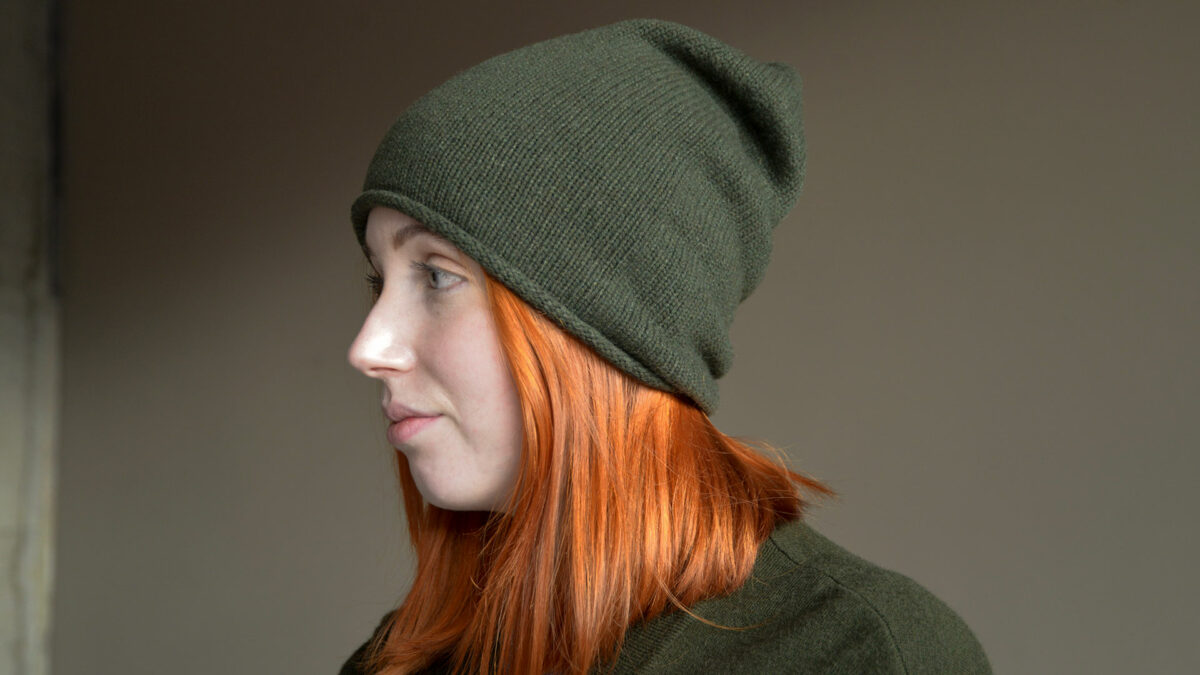 knitted cashmere beanie hat in olive green shown on a model